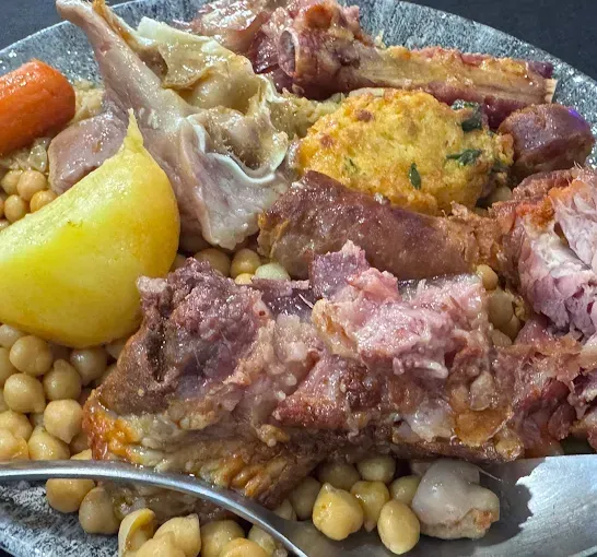 Plato de cocido con garbanzos, carnes y verduras.