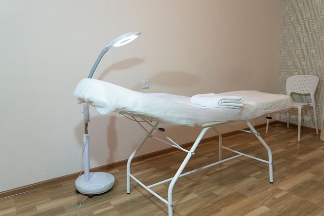 Una mesa de masajes con una lámpara y una silla en una habitación.