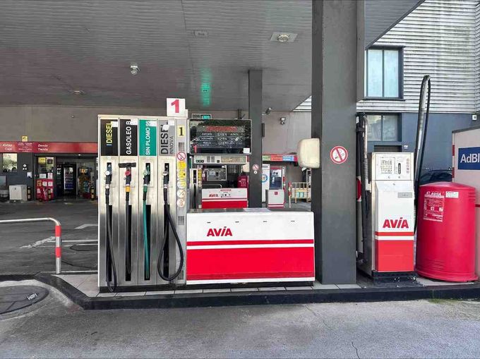 Una gasolinera Avia con surtidores de combustible bajo un toldo, incluido un contenedor de almacenamiento rojo.