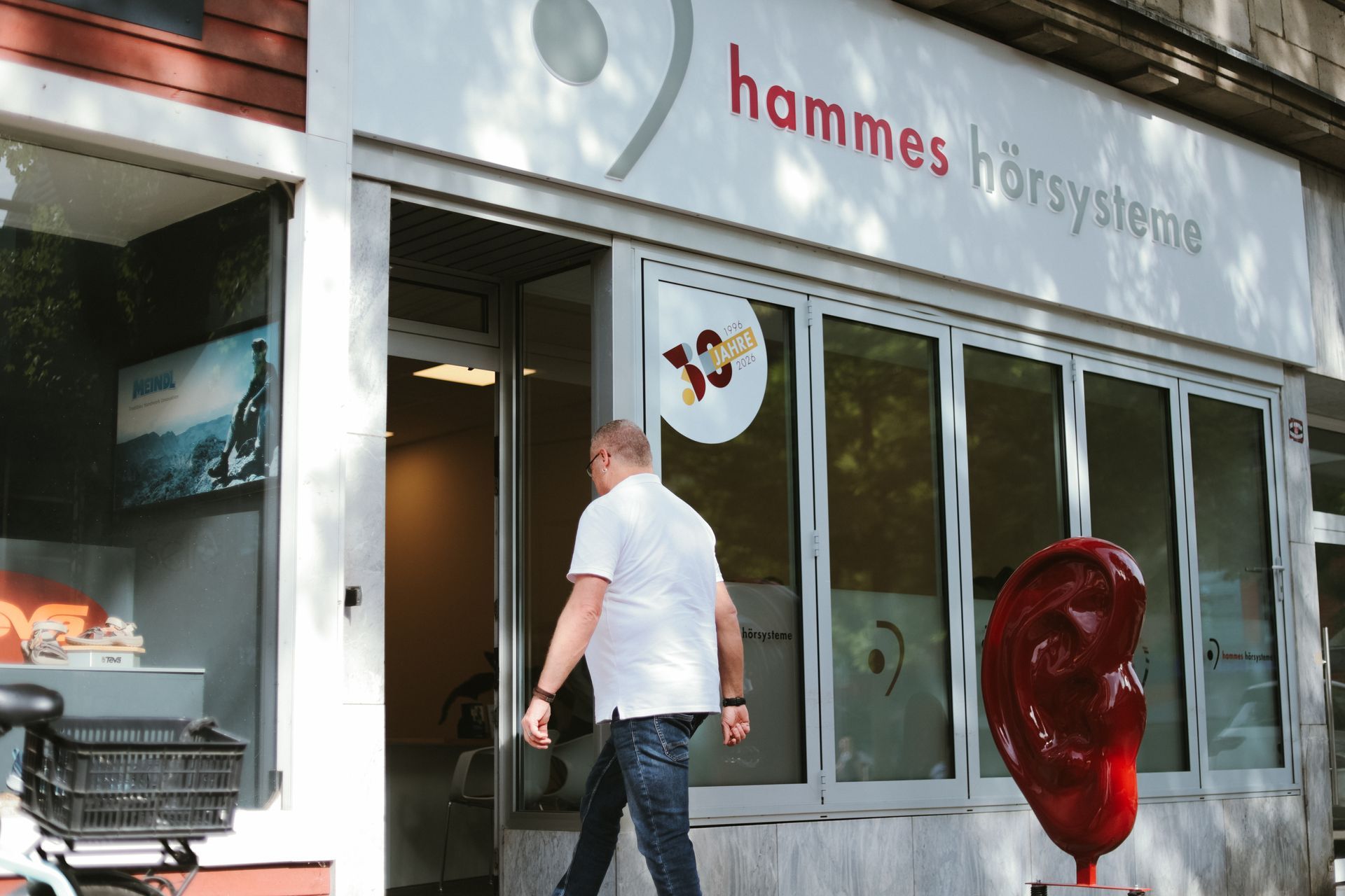Schaufenster mit einem Mann, der an einem gläsernen Eingang vorbeigeht, und einer roten Skulptur draußen