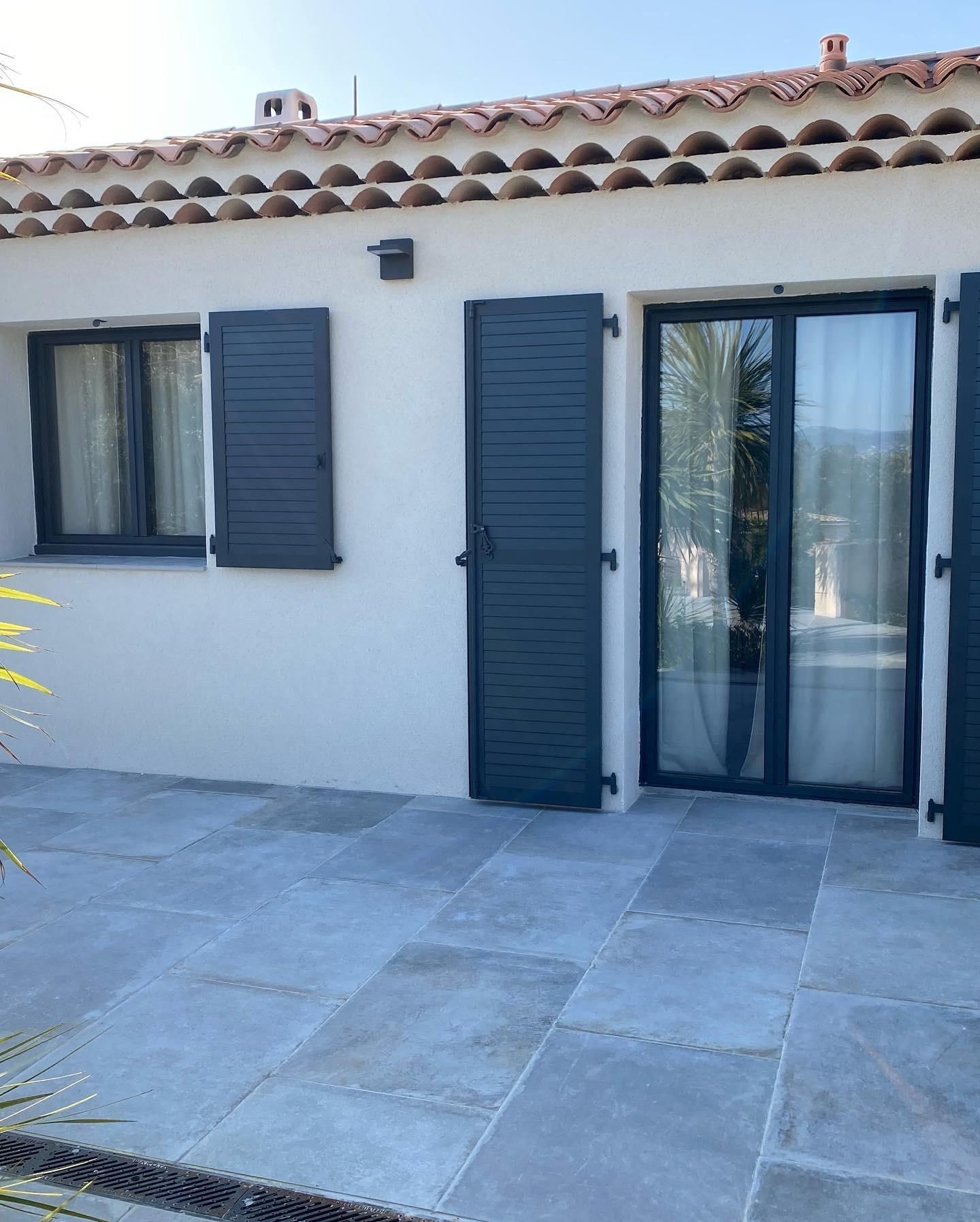 Une façade avec des volets battants noirs