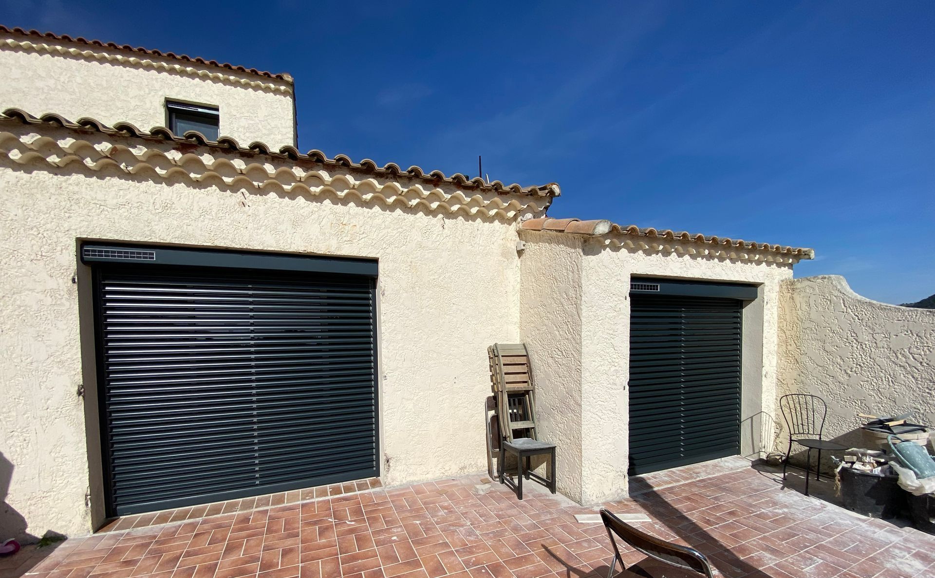 Une façade d'une maison avec des baies vitrées dotées de volets roulants fermés