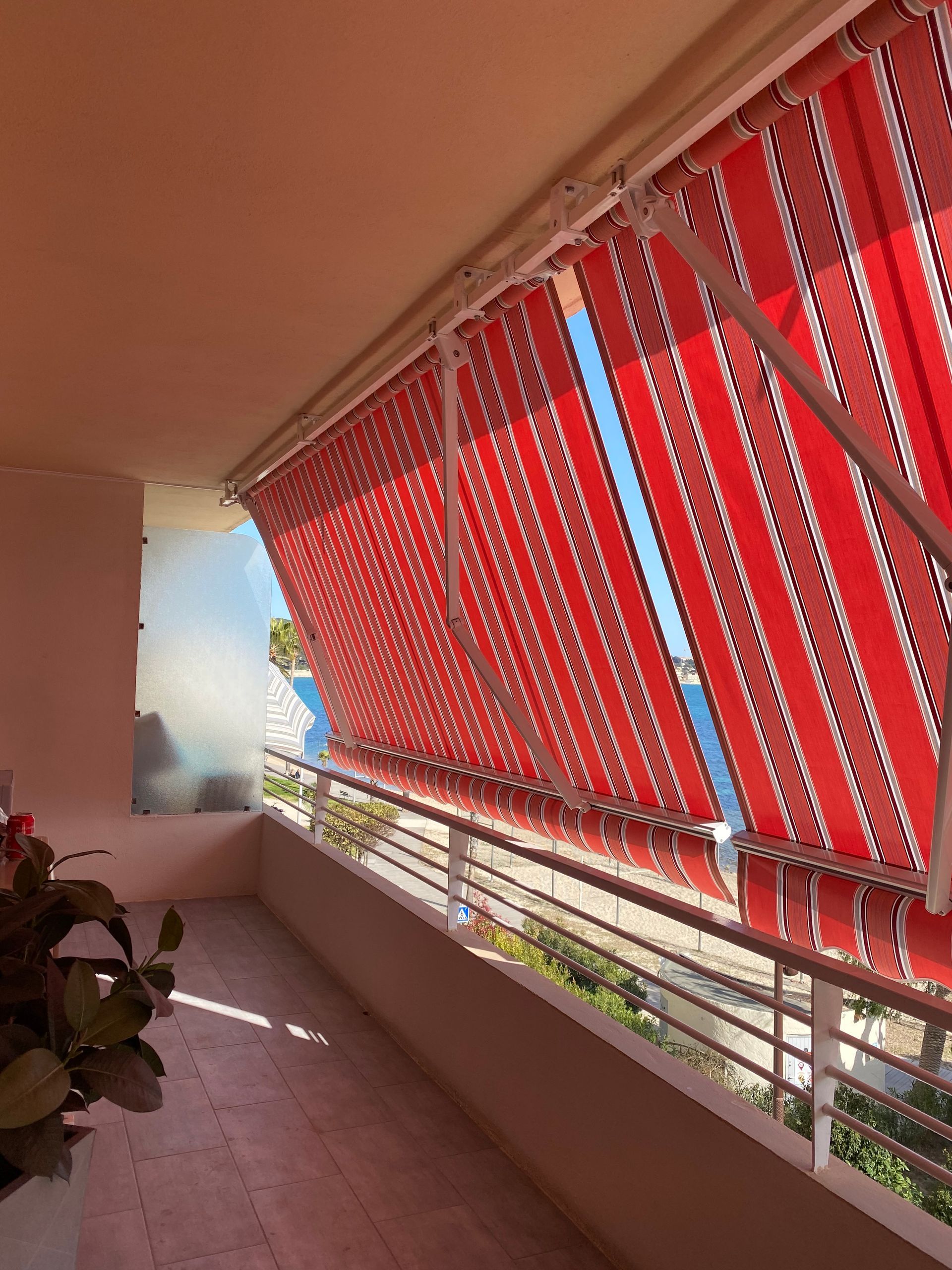 Un store banne rouge rayé sur un balcon