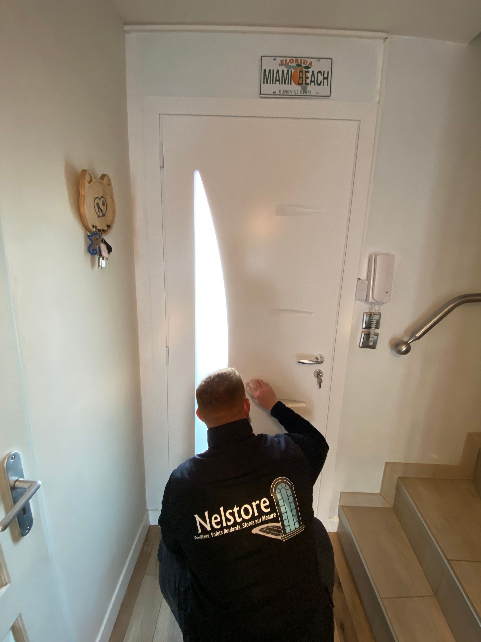 Menuisier qui  procèdent au nettoyage de la porte blanche après installation 
