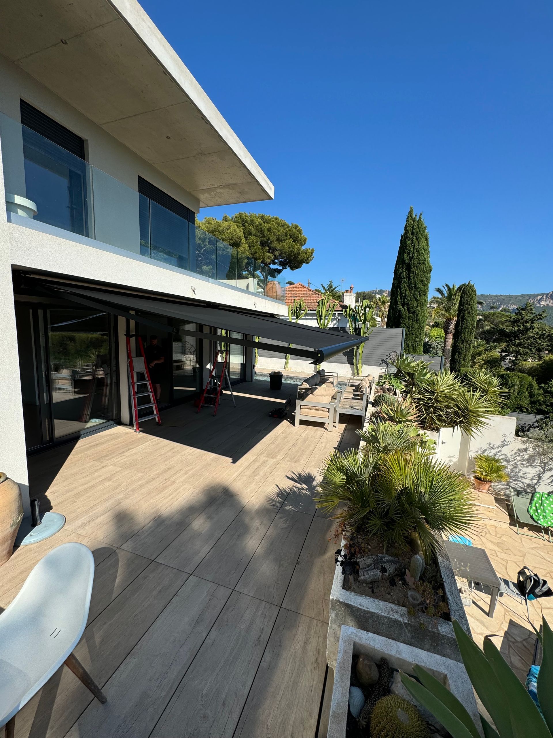 Une store banne noir sur une grande terrasse en bois