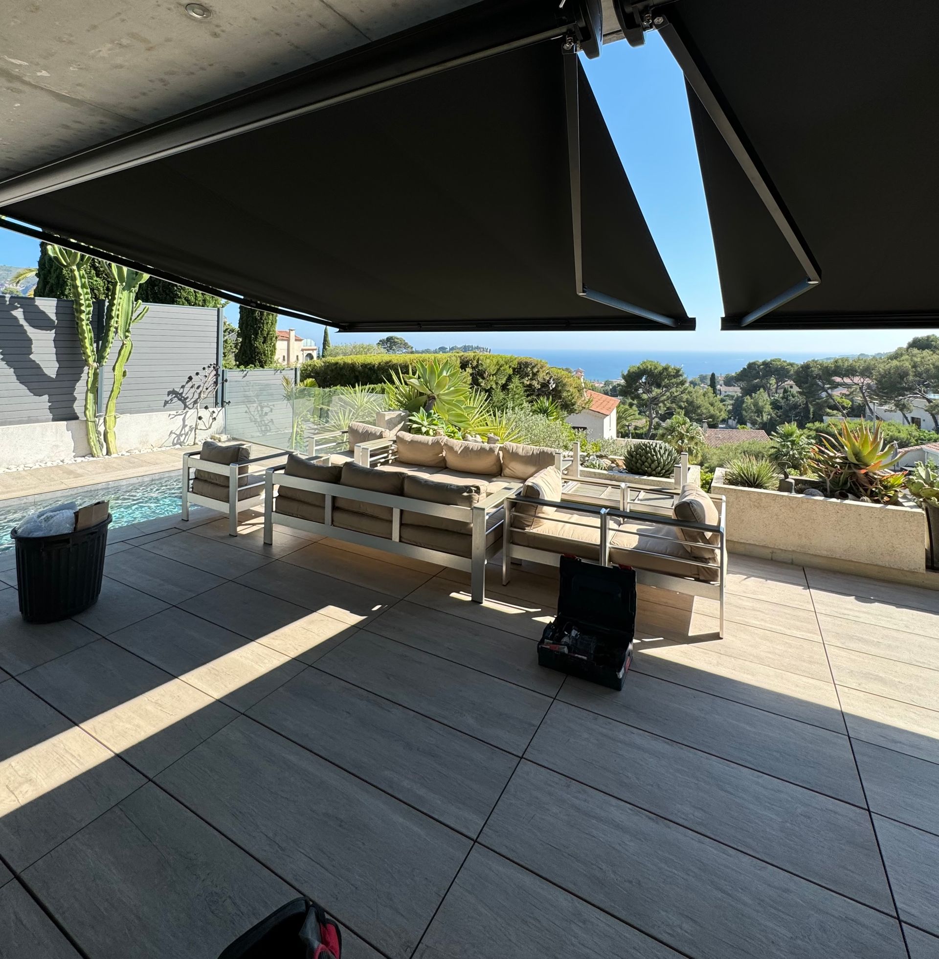 Un store banne noir sur une terrasse avec un salon de jardin