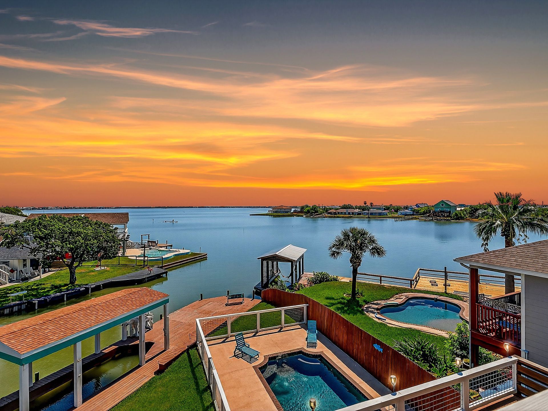 Outdoor dining set on a concrete pad surrounded by green grass and trees under a clear blue sky.