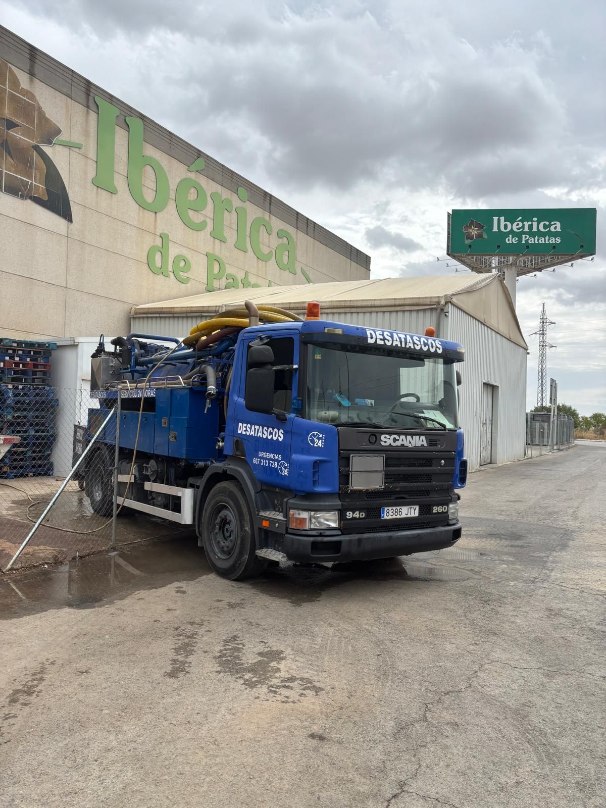 Camión Scania azul estacionado afuera de la tienda Ibérica de Patés, día nublado.