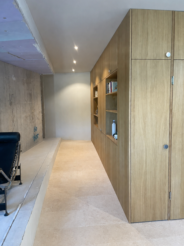 Moderne, minimalistische Küche mit Holzschränken, dunklen Arbeitsplatten und grauem Fliesenboden