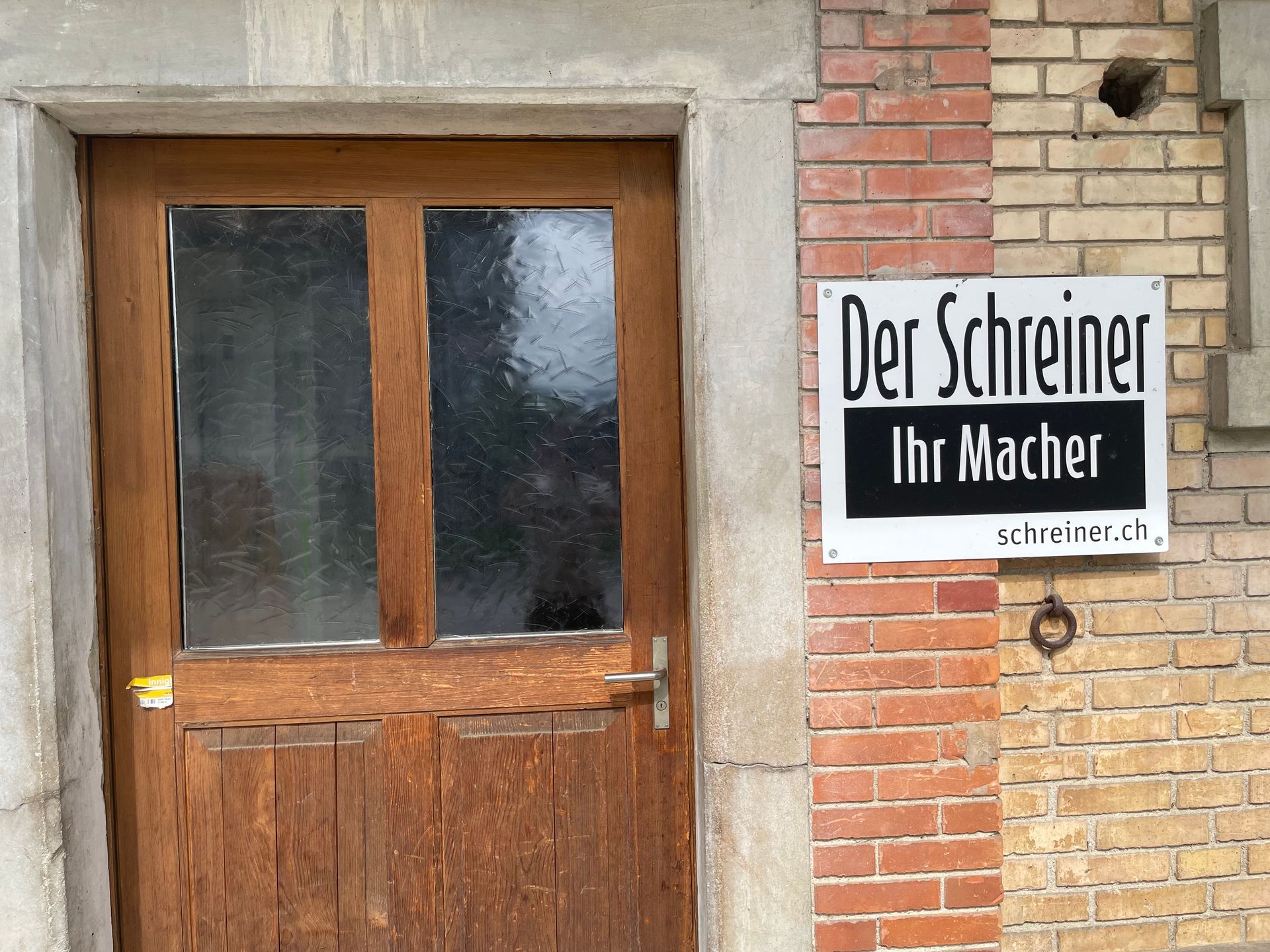 Hölzerne Fussgängerbrücke über einen Gartenteich neben einem Kopfsteinpflasterweg und Grünflächen