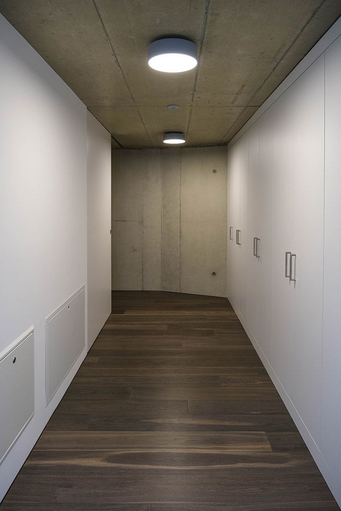 Moderne weisse Küche mit dunklem Fliesenboden, Holzrückwand und Einbaubackofen