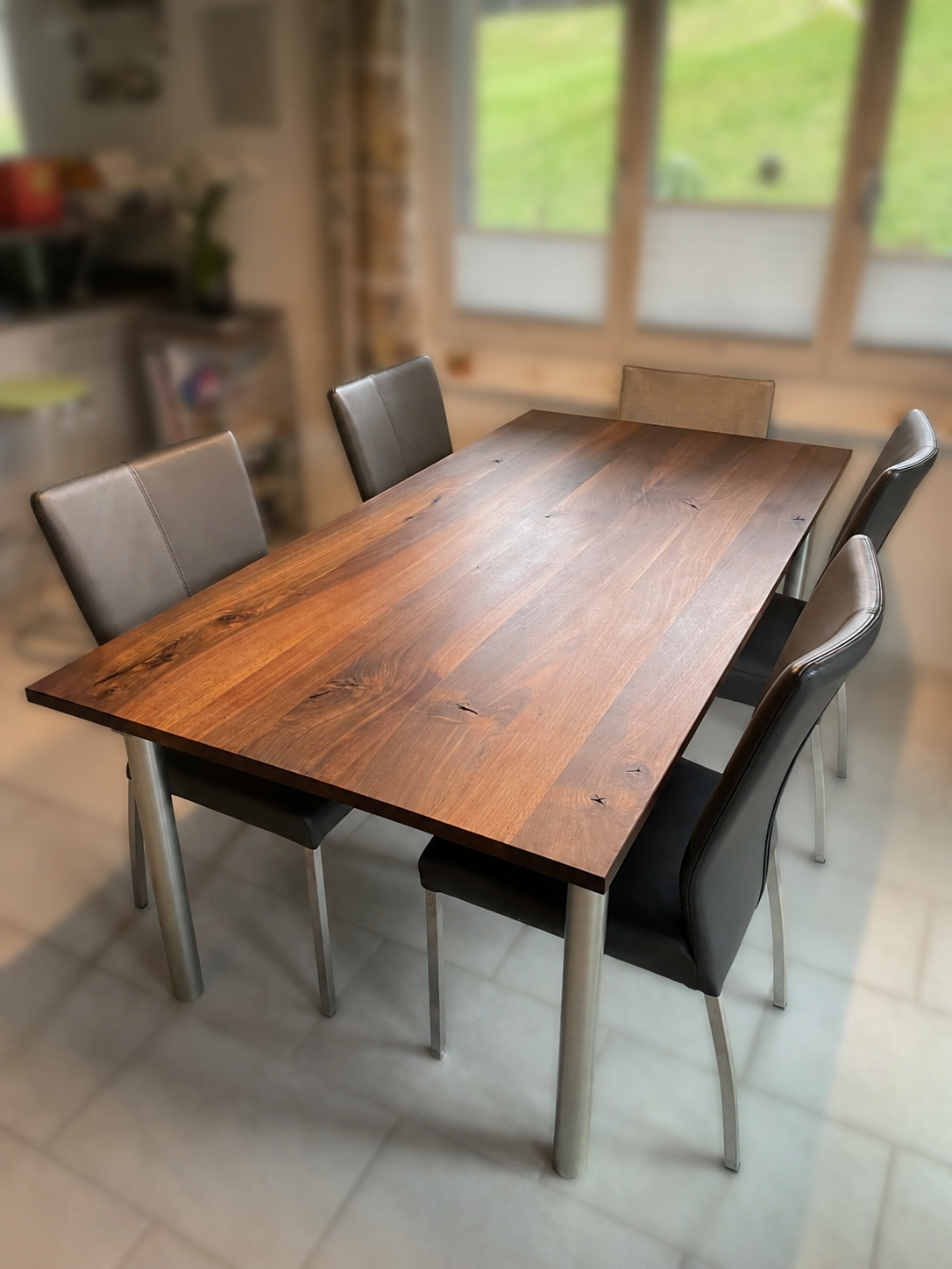 Modernes Esszimmer mit einem langen Holztisch und schwarzen Stühlen auf dunklem Boden