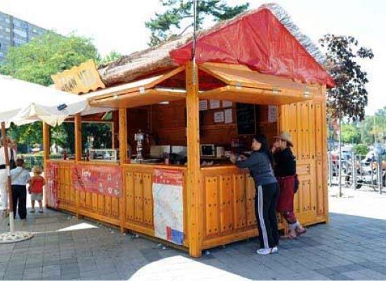 Un grupo de personas de pie frente a un edificio de madera con techo rojo.