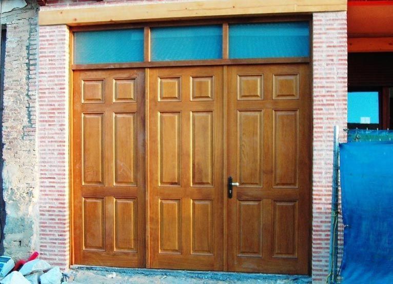 Una puerta de garaje de madera con una pared de ladrillos detrás.