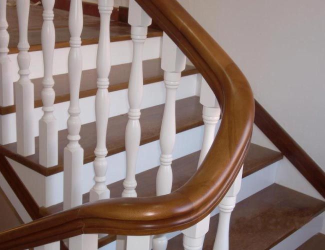 Un primer plano de una barandilla de madera en un conjunto de escaleras.