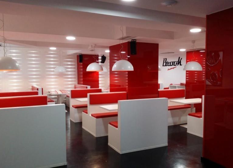 Un restaurante con cabinas rojas y blancas y un cartel que dice banco