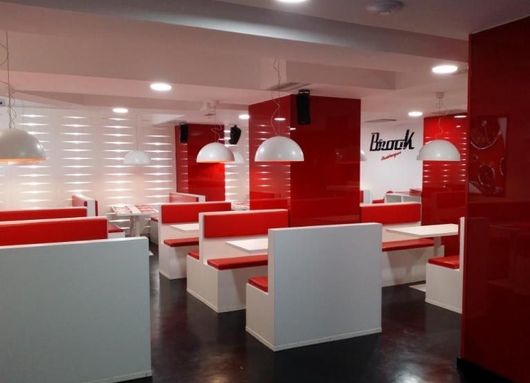 Un restaurante con cabinas rojas y blancas y un cartel que dice banco