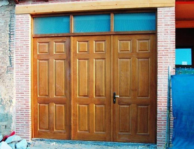 Una puerta de garaje de madera con una pared de ladrillos detrás.