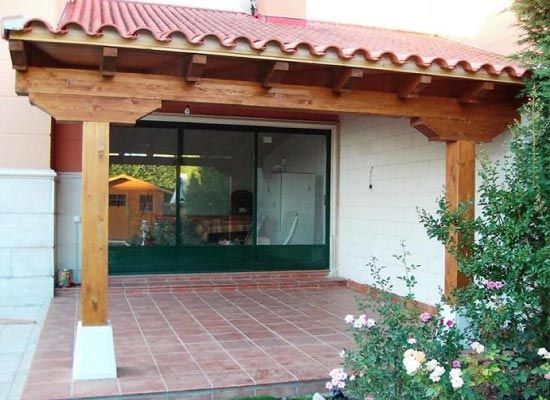 Una casa con techo de tejas rojas y una pérgola de madera