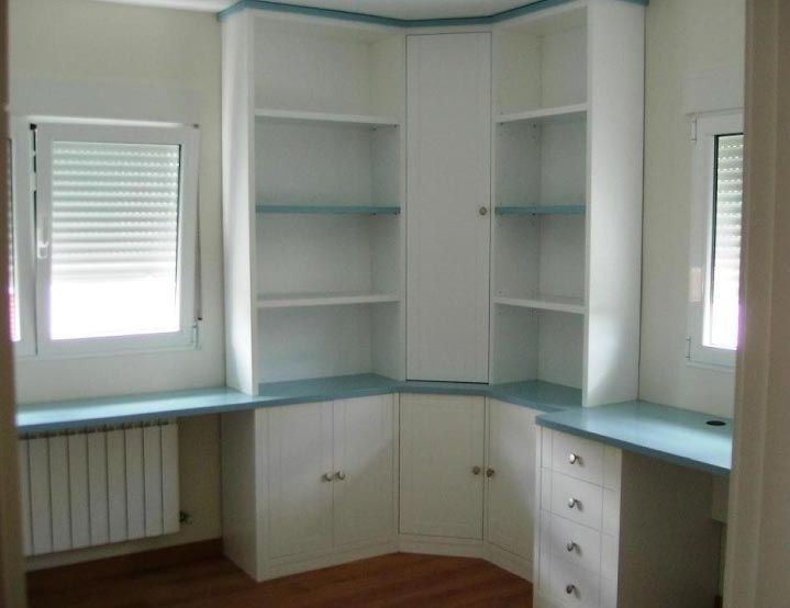 Un rincón de una habitación con estantes y una ventana.