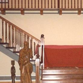 Una escalera con barandilla de madera y una estatua delante de ella.