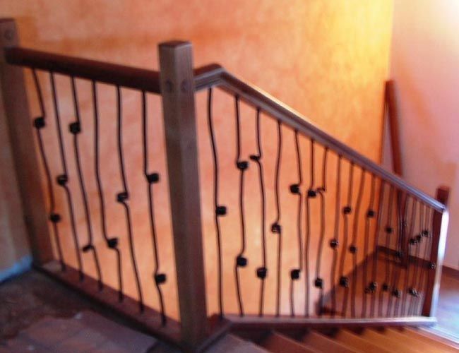 Una escalera de madera con barandilla de hierro forjado