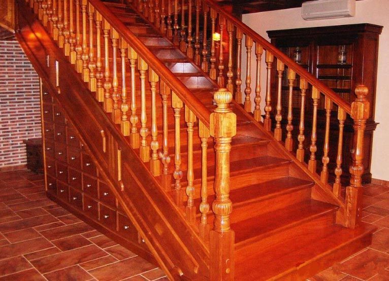 Una escalera de madera con una pared de ladrillos al fondo.
