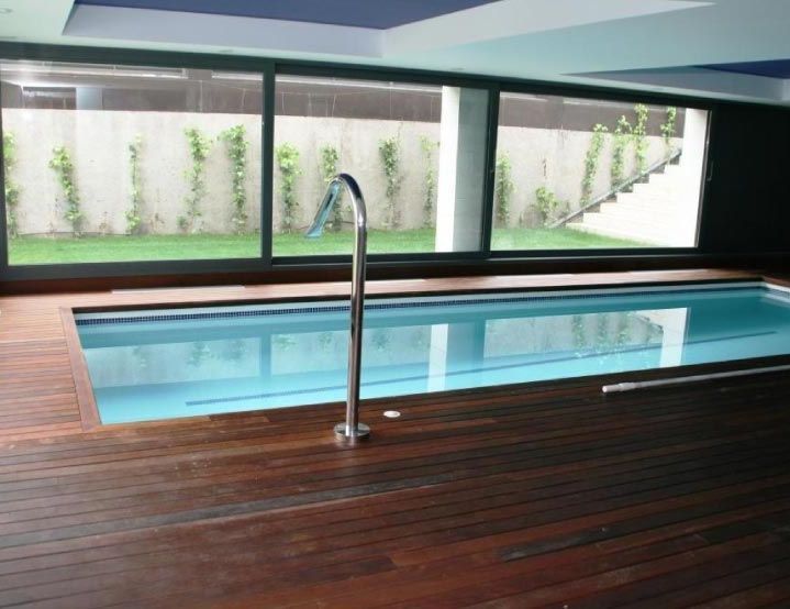 Una gran piscina cubierta con terraza de madera
