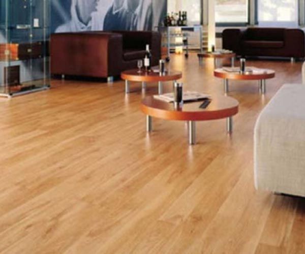 Una sala de estar con suelos de madera y mesas redondas.