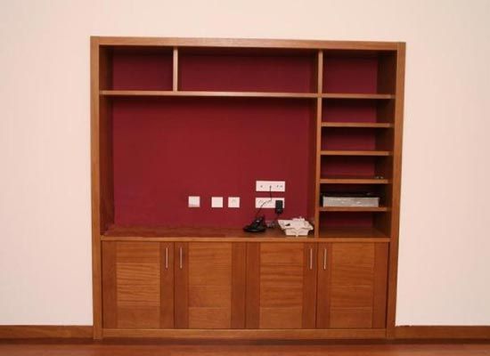 Un centro de entretenimiento de madera con una pared roja detrás.