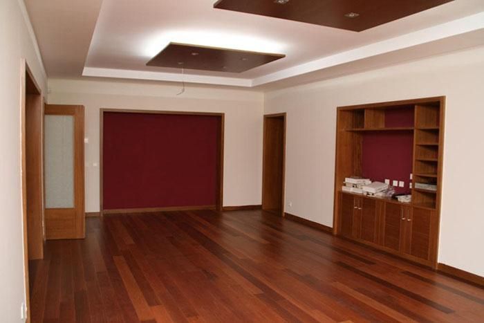 Una habitación vacía con pisos de madera y una pared roja.