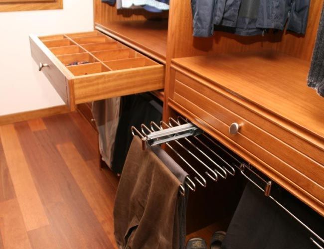 Un cajón en un armario con pantalones colgando de él.