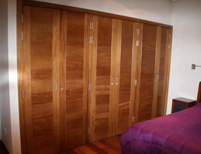 Un dormitorio con una cama morada y armarios de madera.