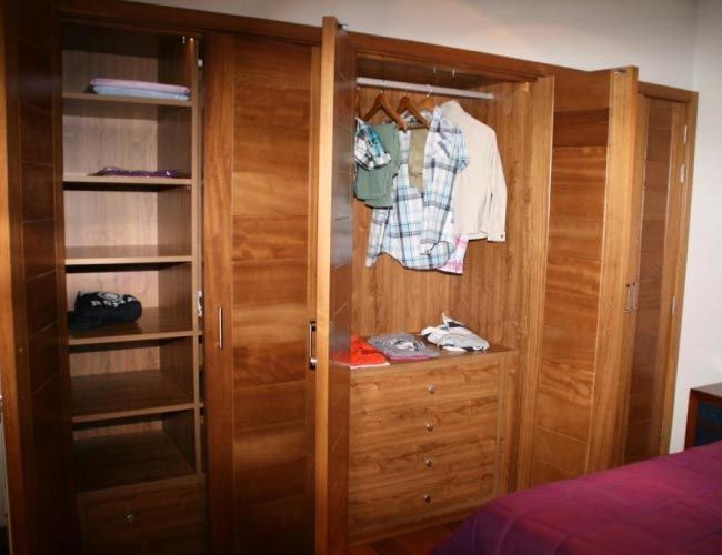 Un armario de madera con ropa colgada en él.