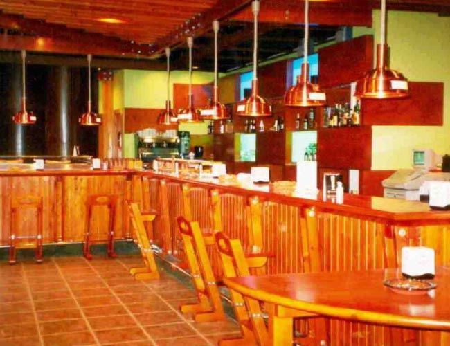 Un restaurante con una larga barra de madera y mesas.