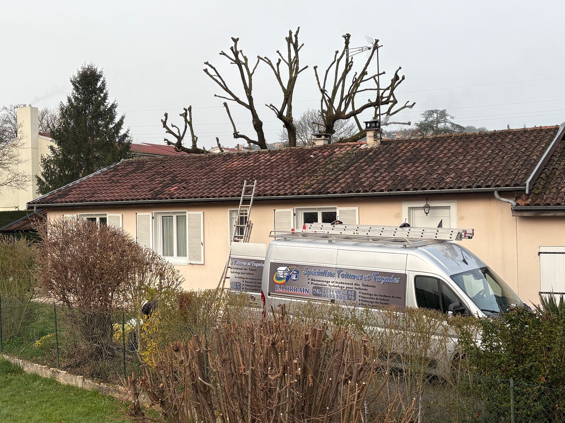Une camionnette de service blanche garée devant une maison beige au toit de tuiles rouges.