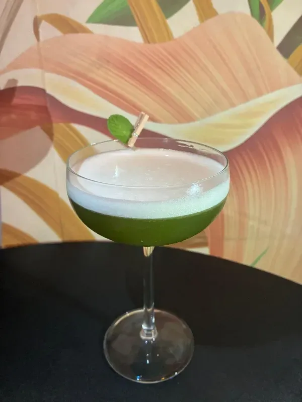 Un cóctel por capas en un vaso acanalado, coronado con una rodaja de cítricos deshidratados