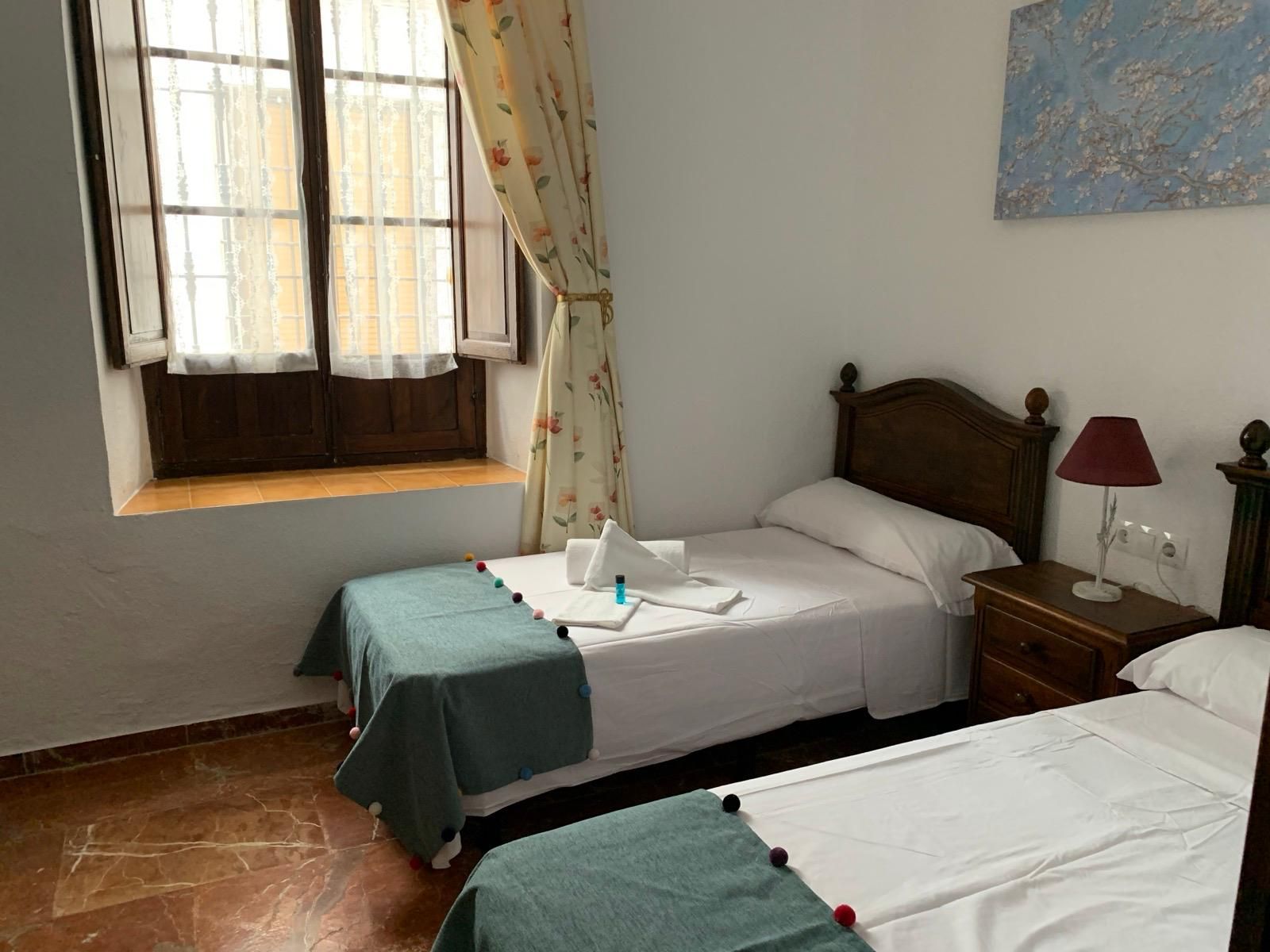 Un dormitorio con dos camas, una mesita de noche y una ventana.