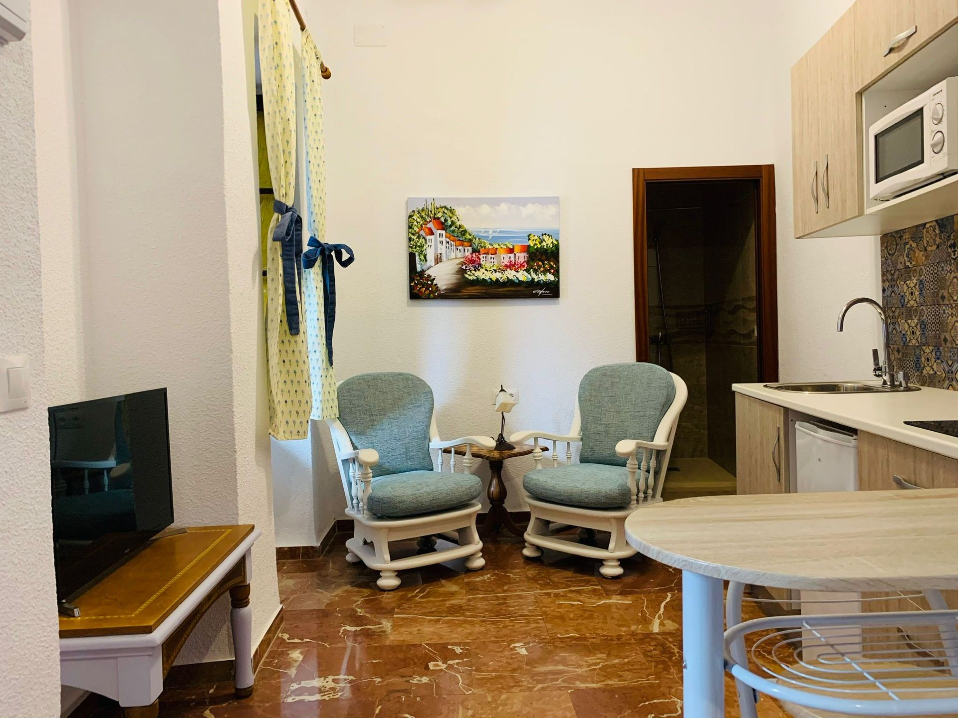 Una sala de estar con dos sillas, una mesa y un televisor.