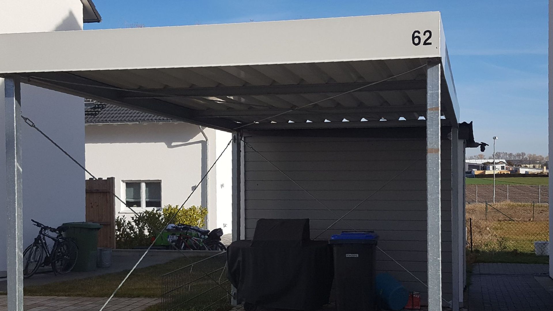 Vor einem Haus steht ein Carport mit der Nummer 62.