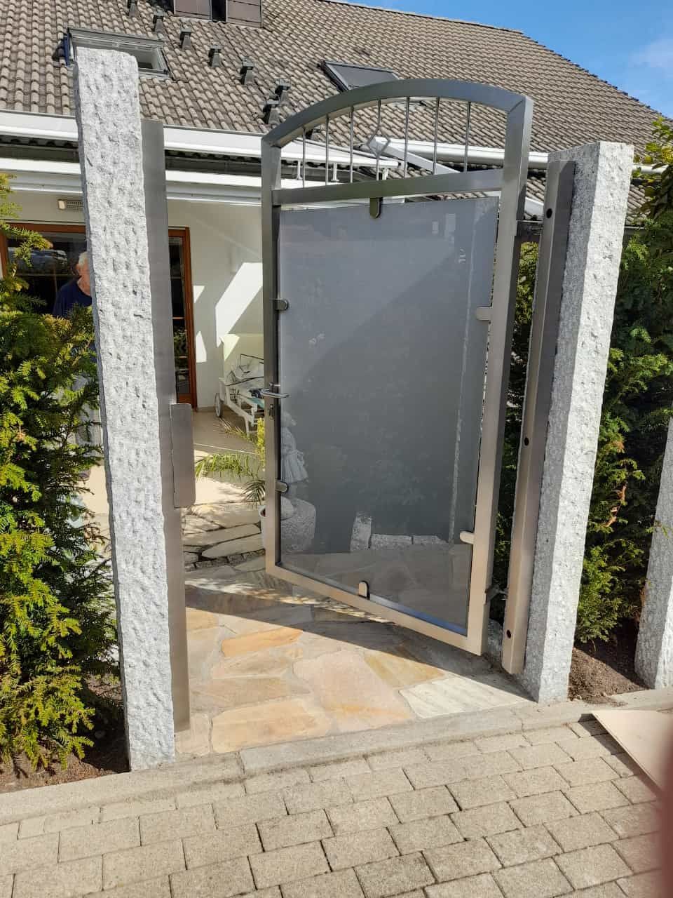 Vor einem Haus steht ein Edelstahltor offen.