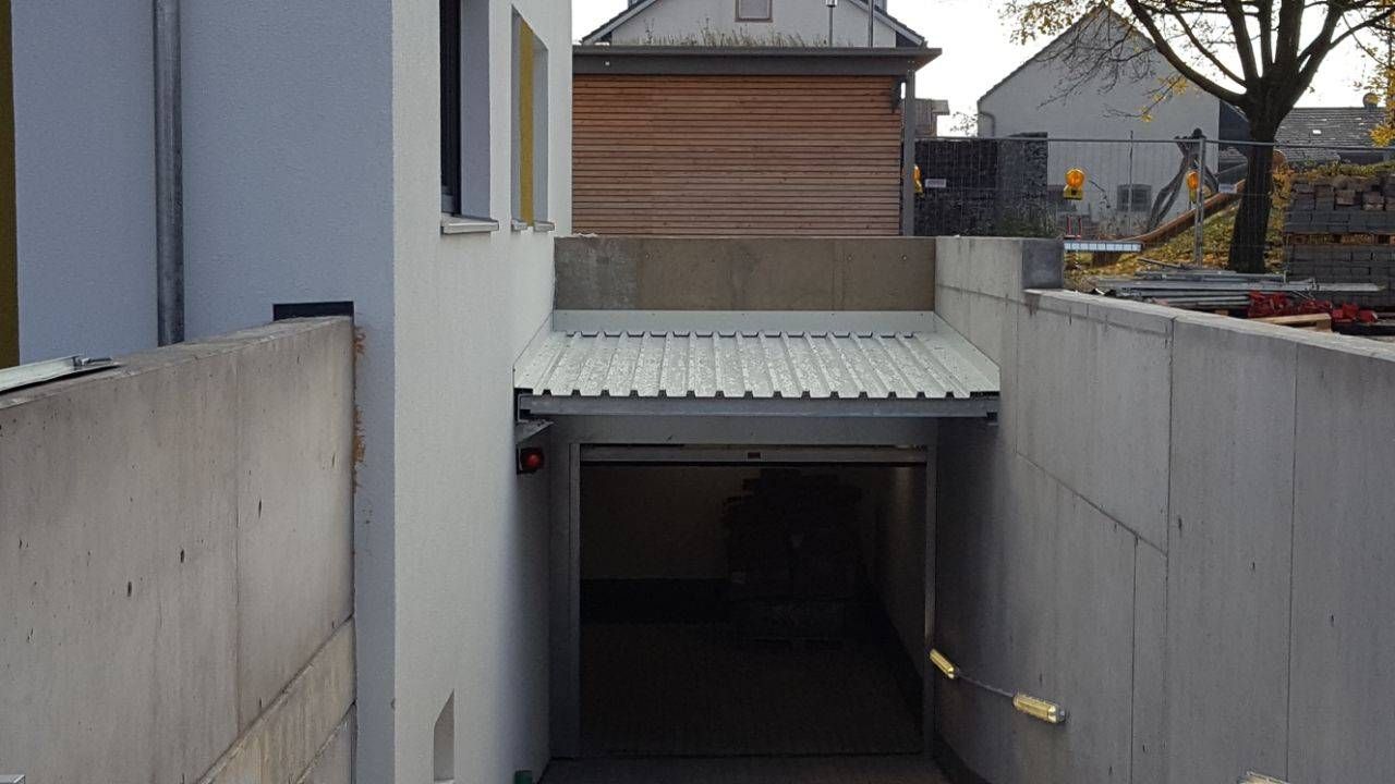 ein Betontunnel, der zu einer Garage mit weißem Dach führt.
