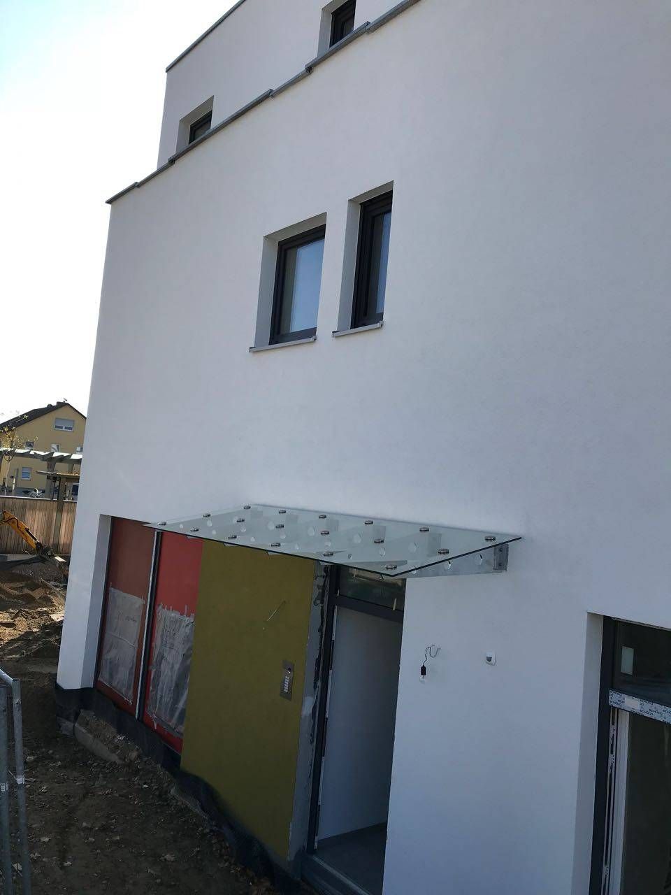 ein weißes Gebäude mit zwei Fenstern und einem Glasdach