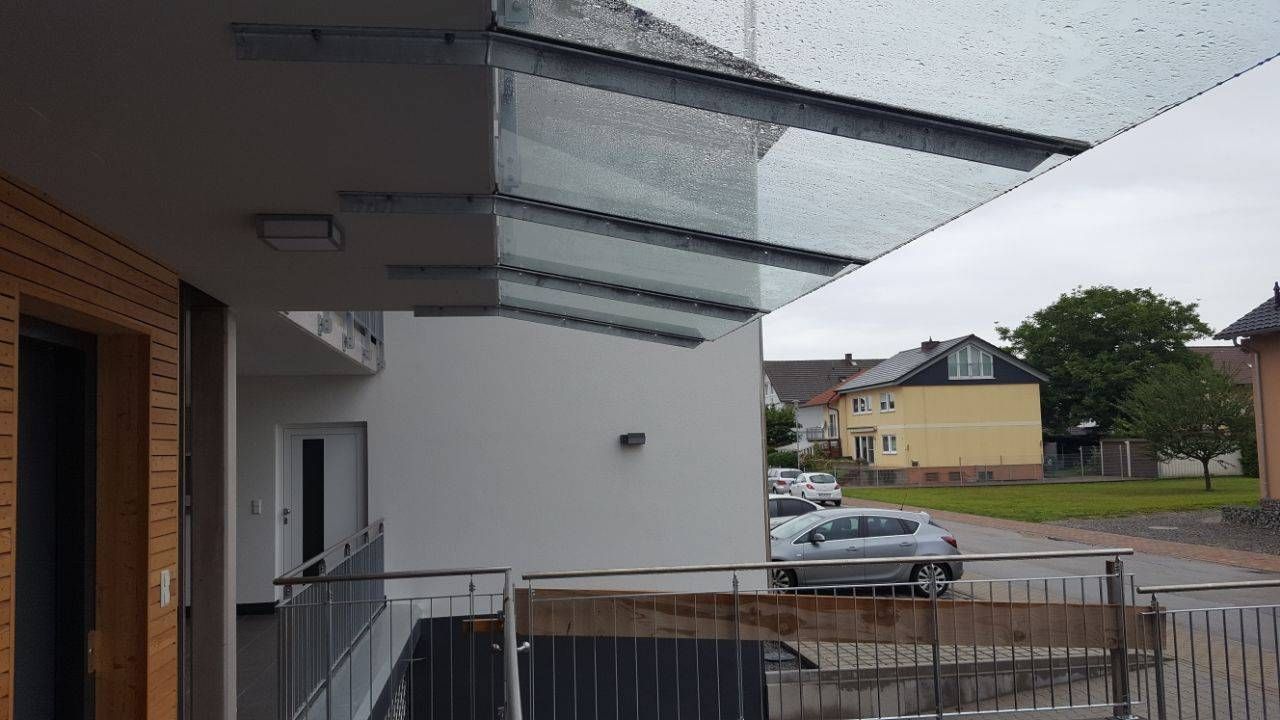 Ein Auto parkt unter einem Glasdach an der Seite eines Gebäudes.