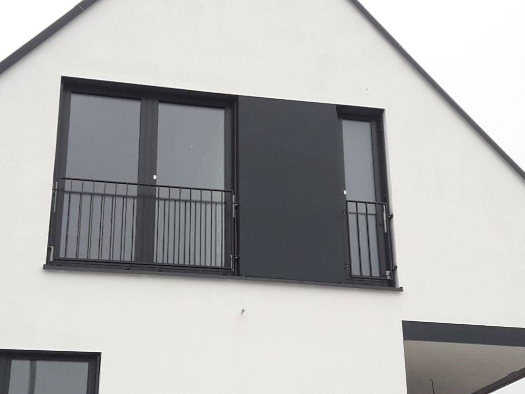 ein weißes Haus mit schwarzen Fenstern und einem Balkon