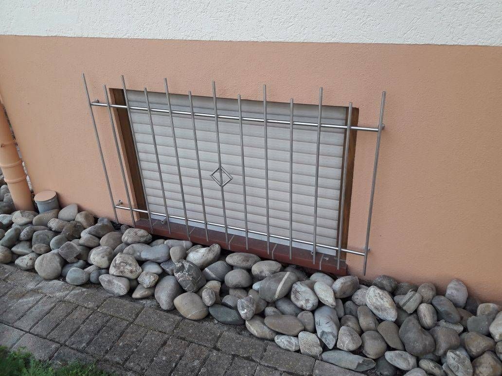 Ein Fenster mit einem Metallgitter darauf ist von Felsen umgeben.