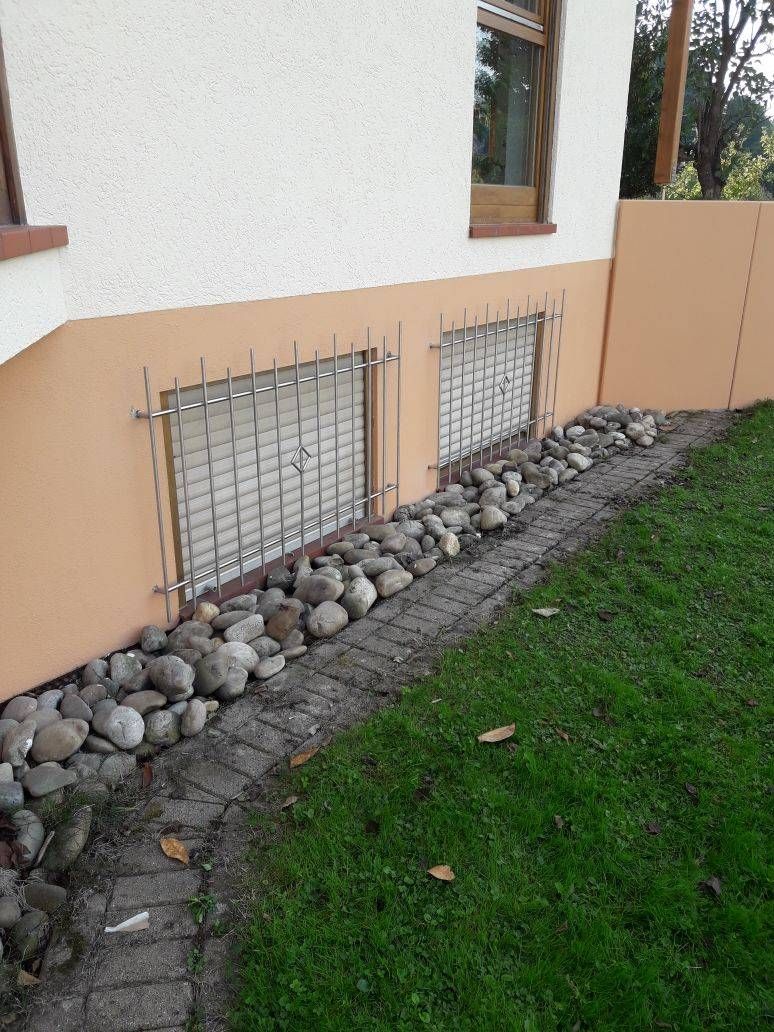 ein Haus mit einer Backsteinmauer und einem Steinweg davor.