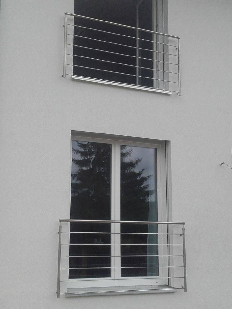 ein weißes Gebäude mit einem Fenster und einem Geländer aus Edelstahl