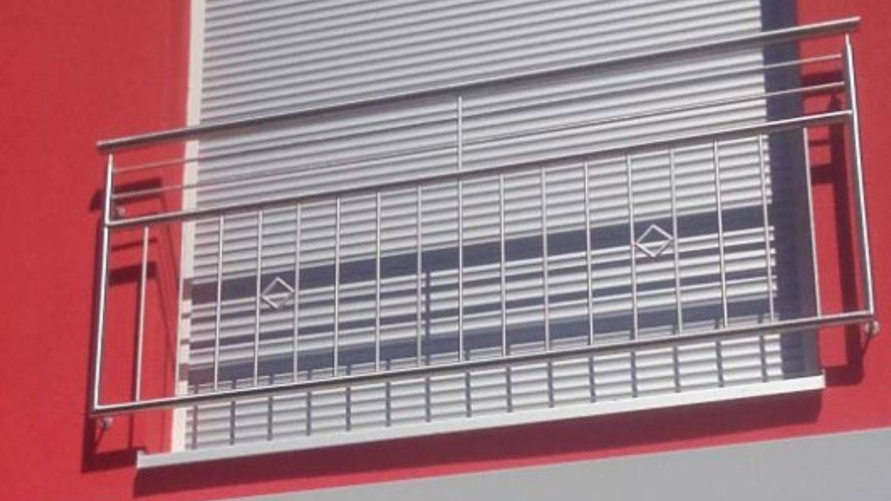 ein Balkon mit einem Edelstahlgeländer auf einem roten Gebäude