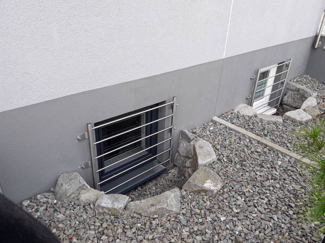 An der Seite eines Gebäudes befindet sich ein Fenster mit einem Metallzaun.